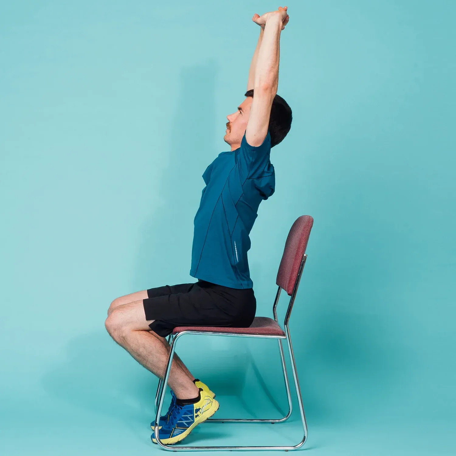 man lifting arms above head in a chair
