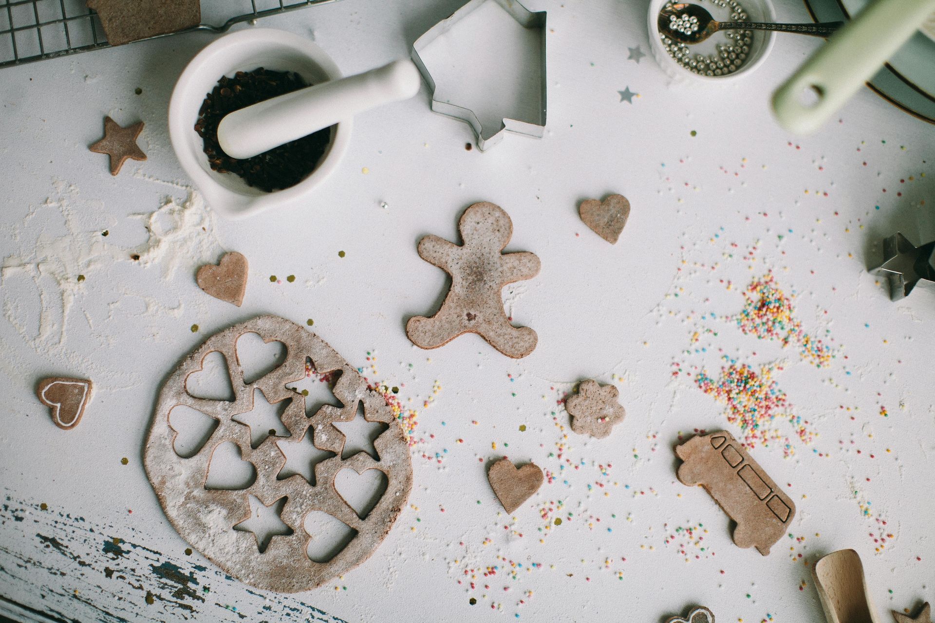 Various cinnamon figures sit on a table along with dust and crumbs from other food items. A pestle and mortar is there.