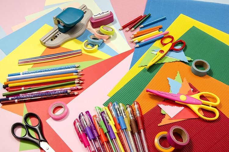 Various pens, markers and scissors sit on the floor with construction paper
