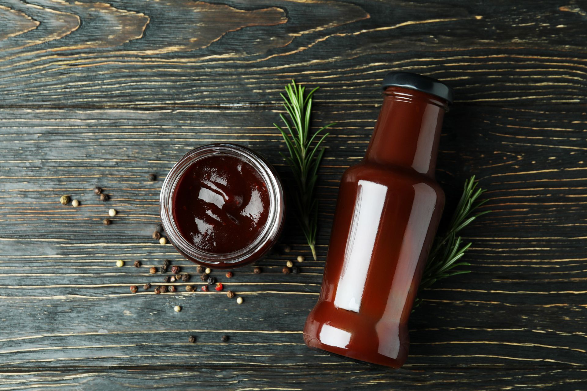 A bottle of barbecue sauce and a bowl of barbecue sauce on a wooden table