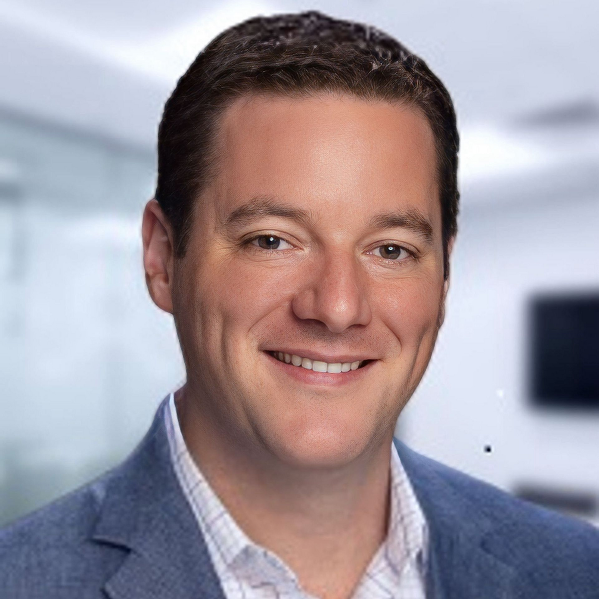 Smiling man in a blue blazer against a softly blurred office background