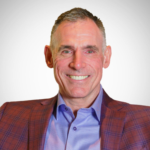 Smiling man in a red plaid blazer and blue shirt against a white background