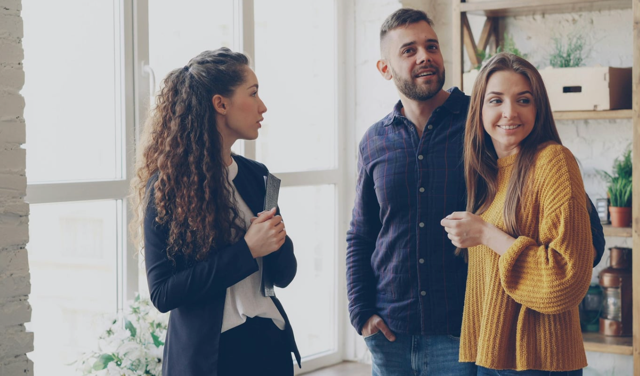 Three people standing together in a bright room, smiling and talking casually
