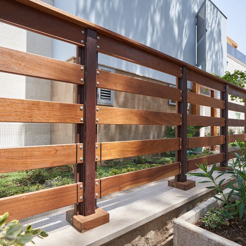 Wooden slat fence with dark metal posts along a modern building exterior.