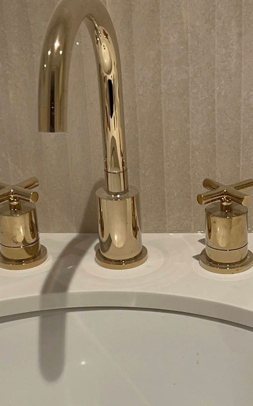 Polished gold bathroom faucet with two matching handles over a white sink