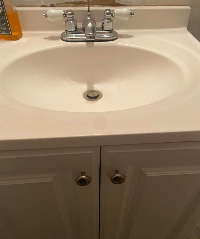 White bathroom sink with chrome faucet and cabinet doors beneath.