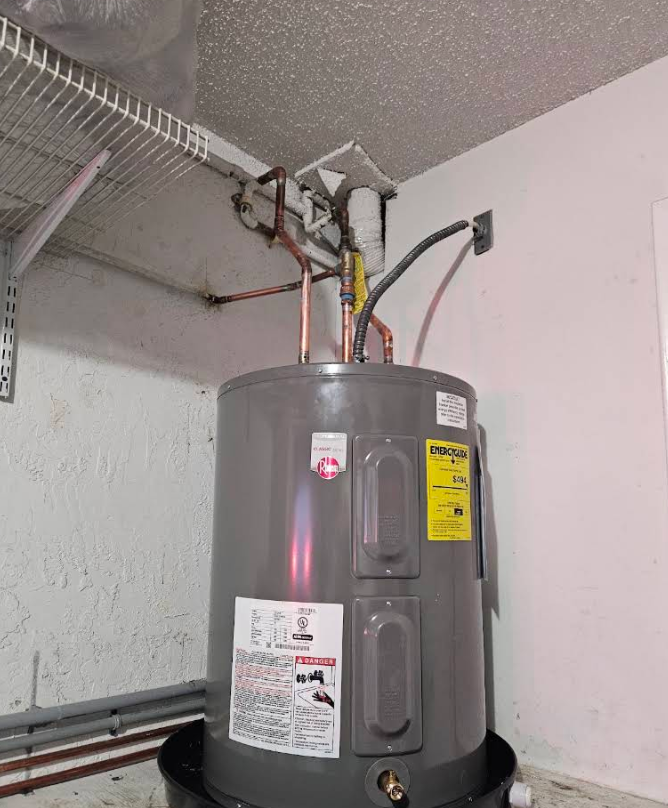 Gray water heater with pipes and labels in a utility closet