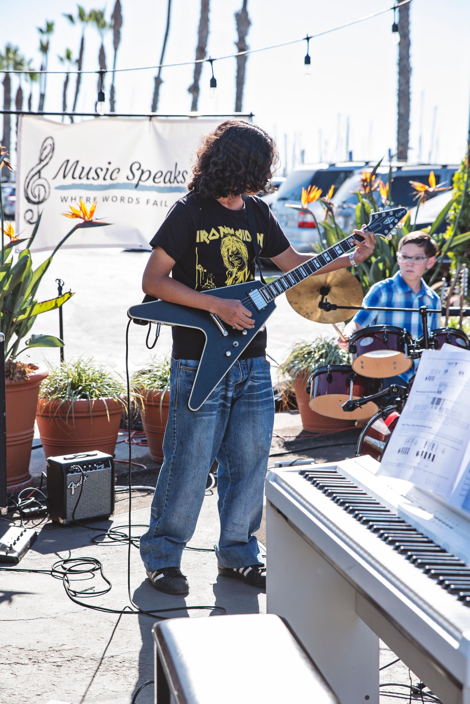 A man playing a guitar in front of a sign that says music speaks