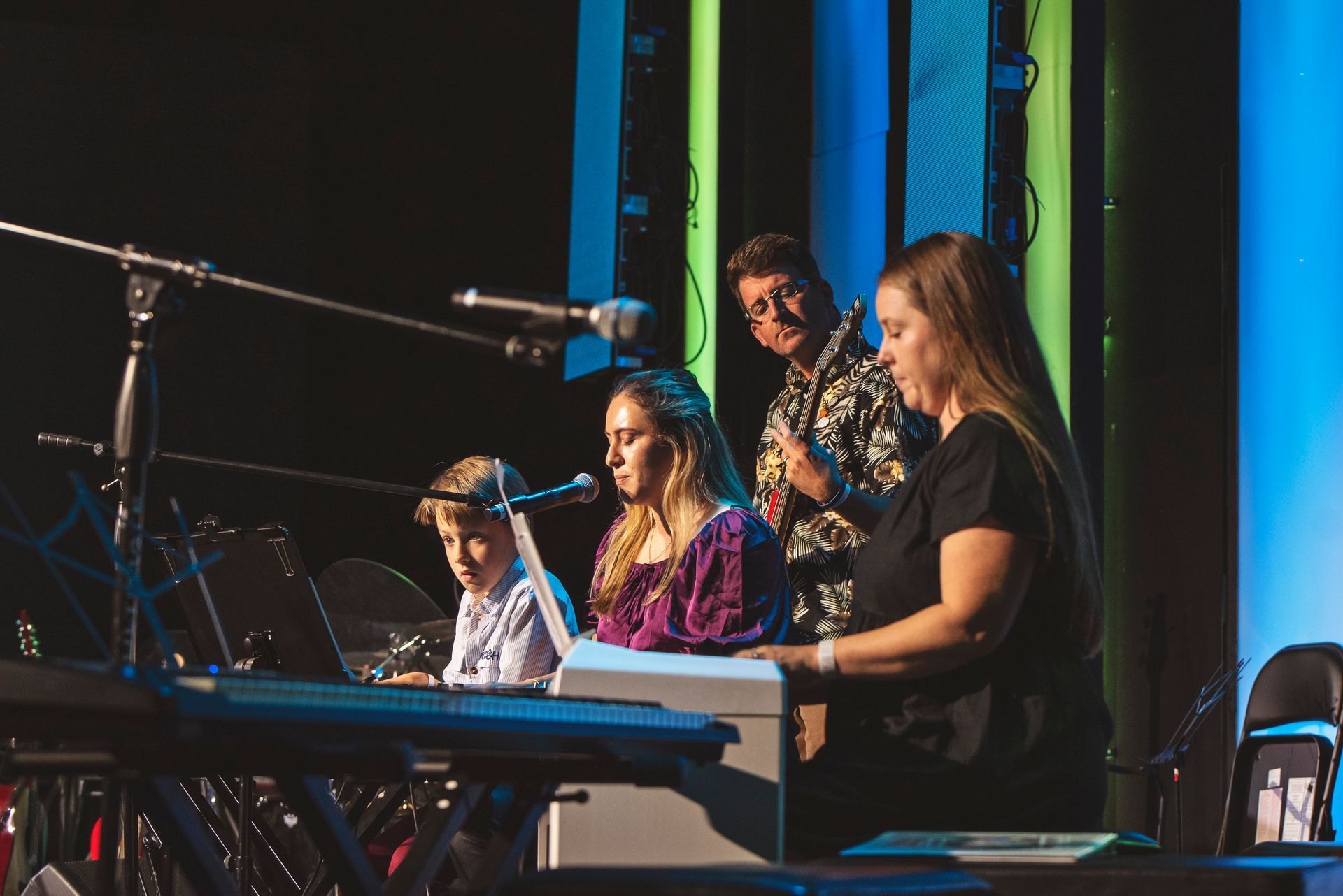 A group of people are playing keyboards on a stage.
