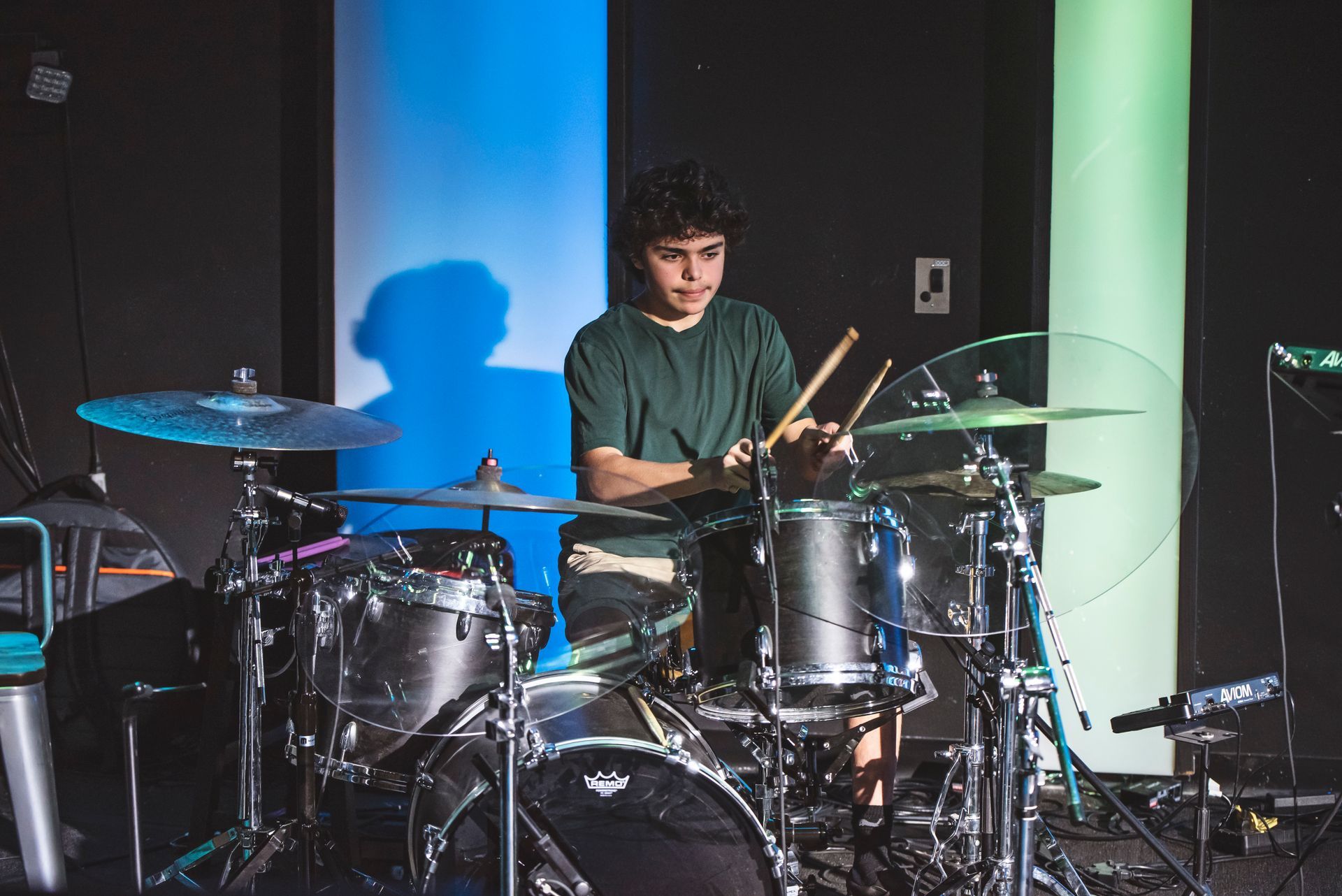 A young man is playing drums on a stage.