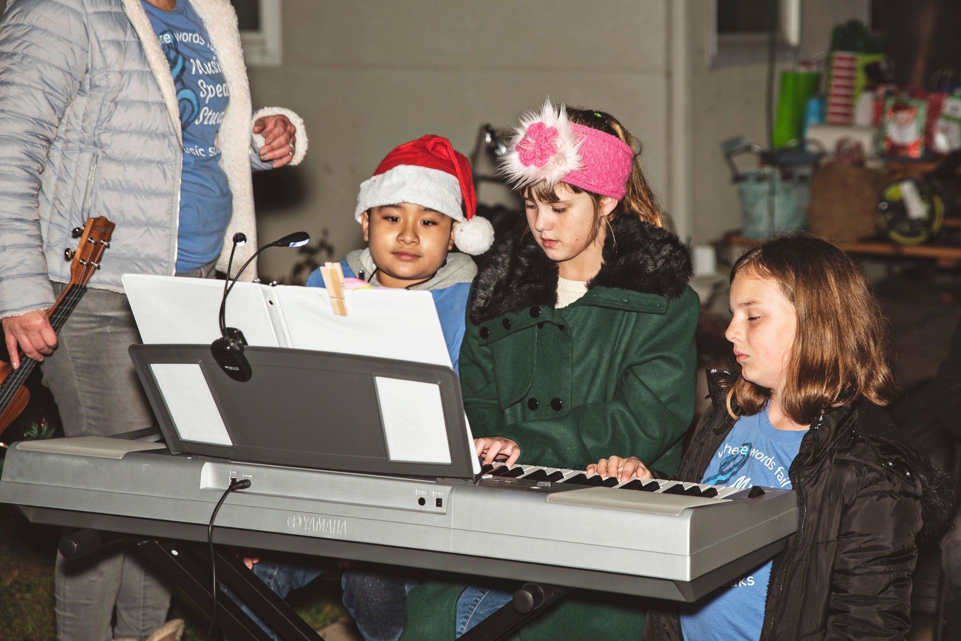 A group of children are singing christmas carols on a keyboard.