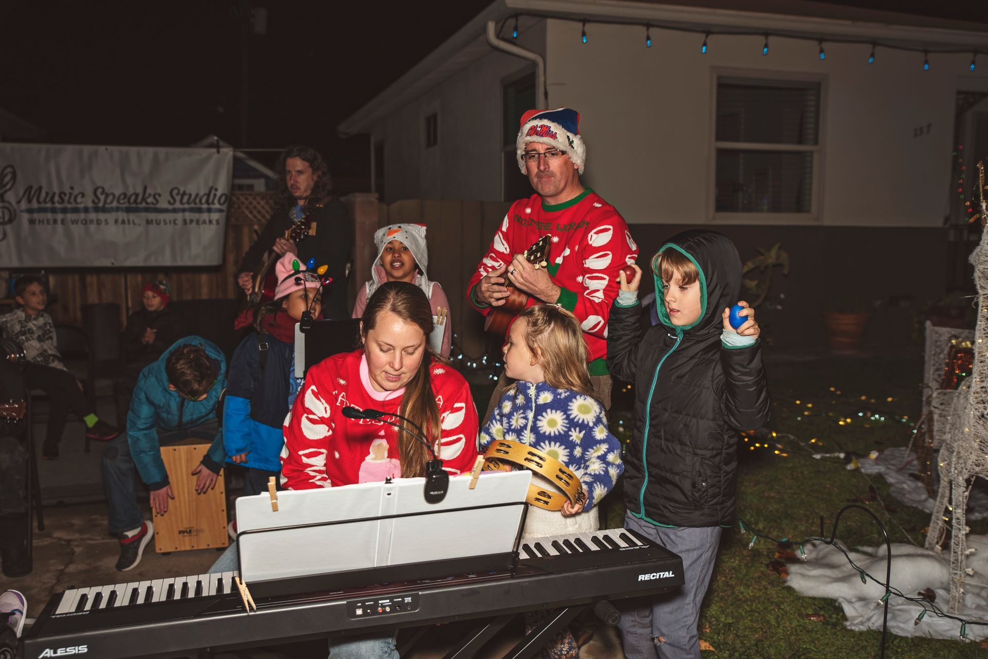 A woman is playing a piano in front of a group of people.