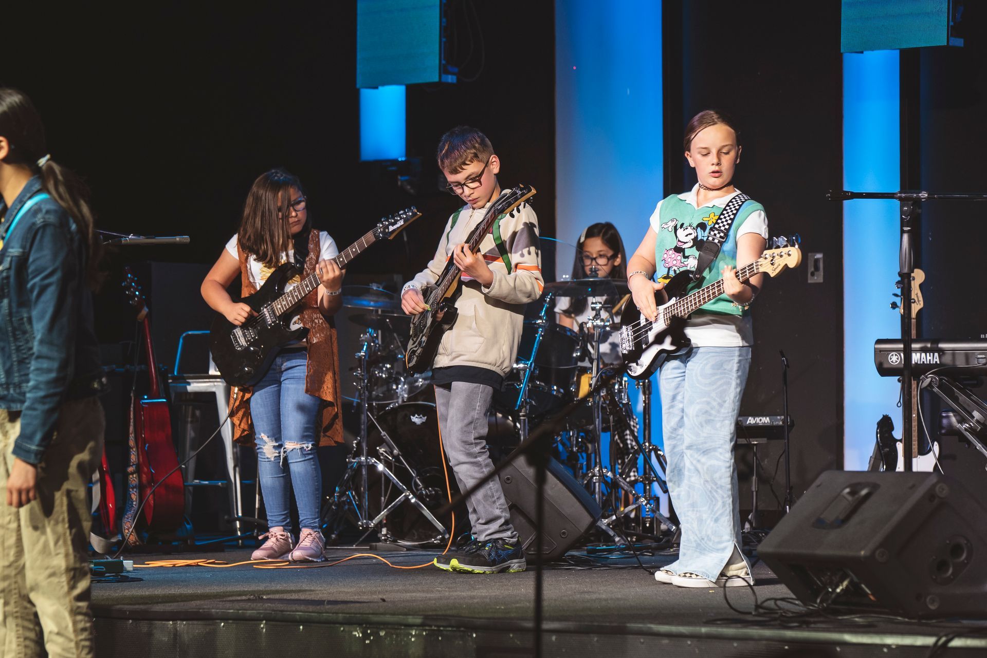A group of young people are playing guitars on a stage.