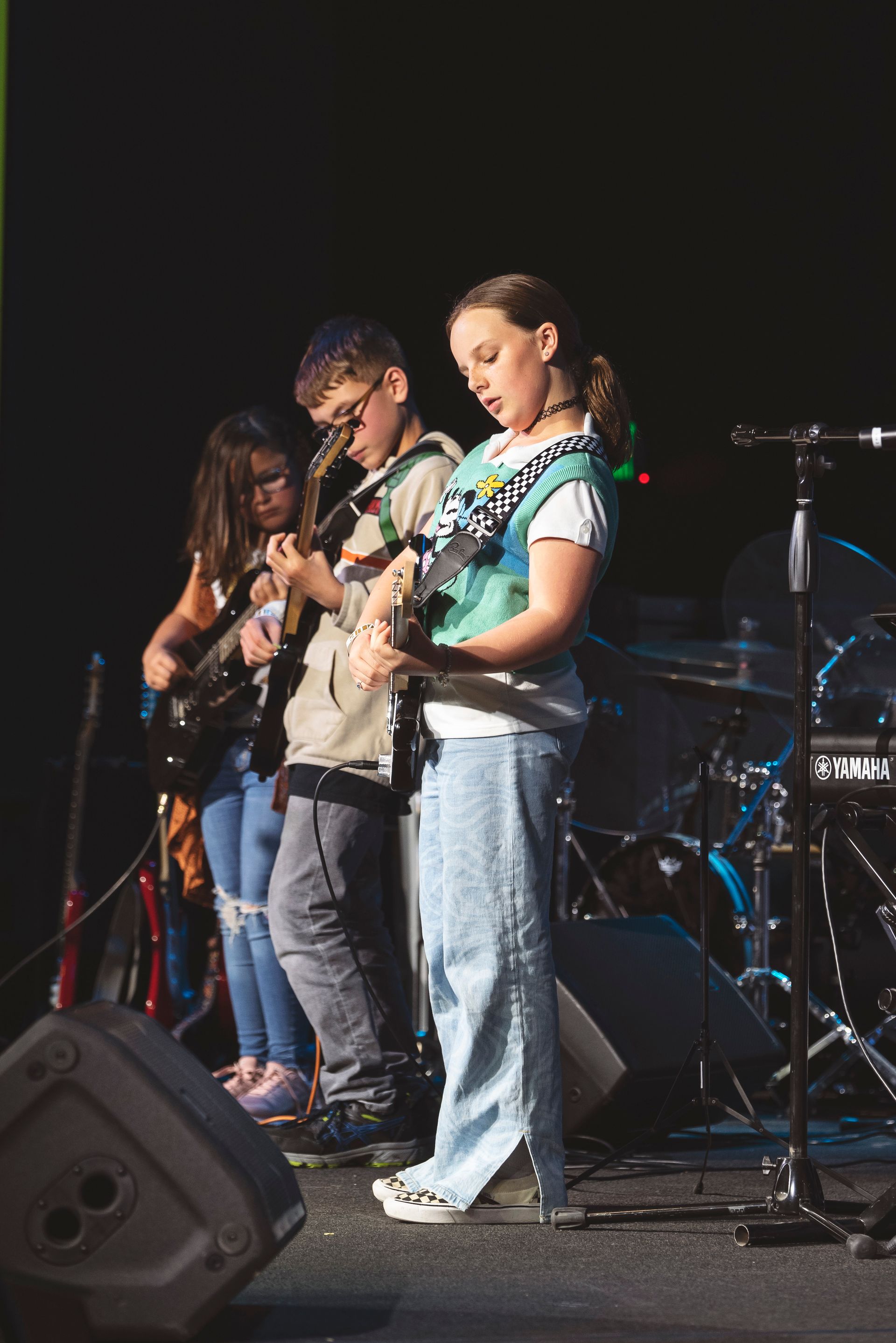 A group of young people are playing guitars on a stage.