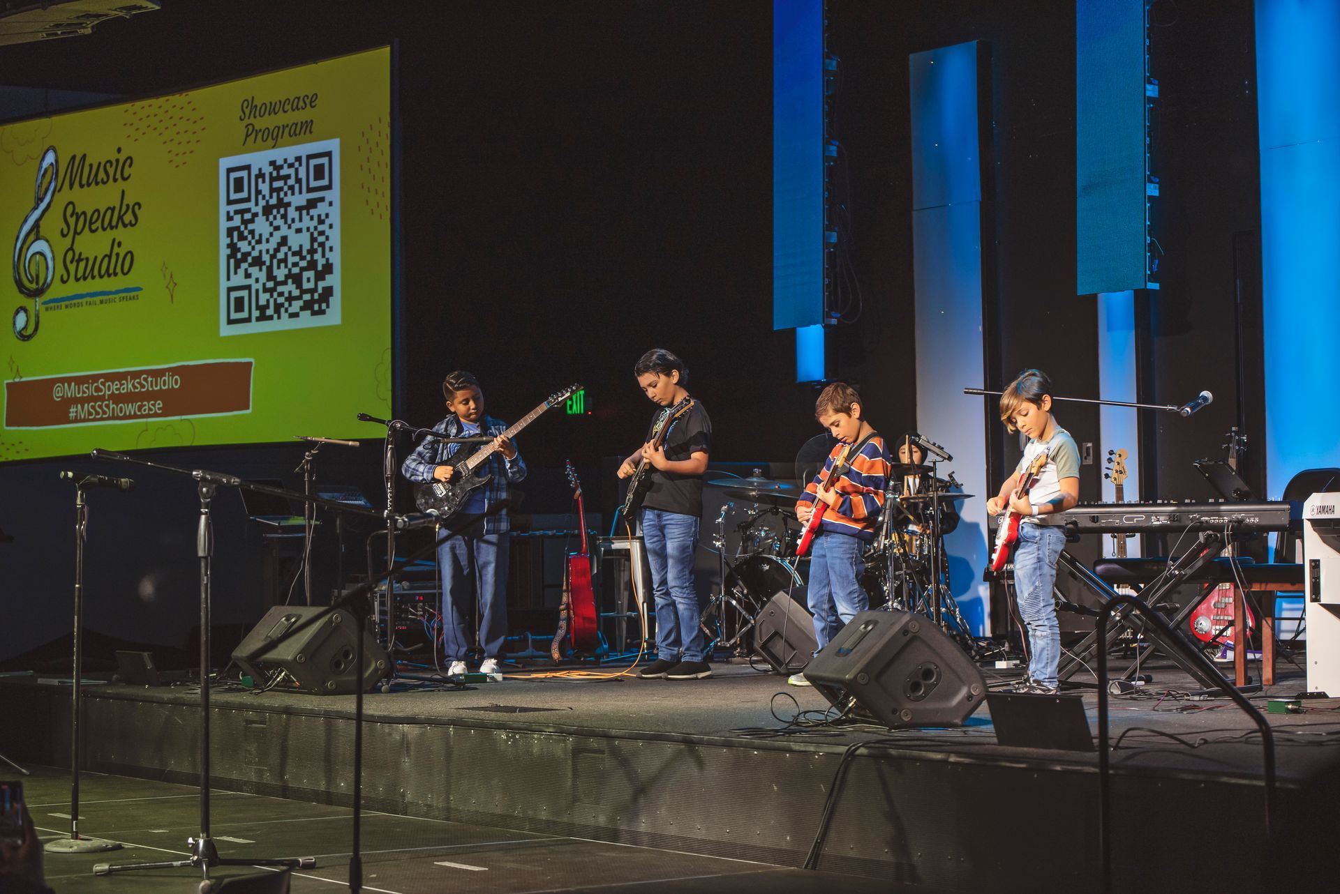 A group of young men are playing guitars on a stage.