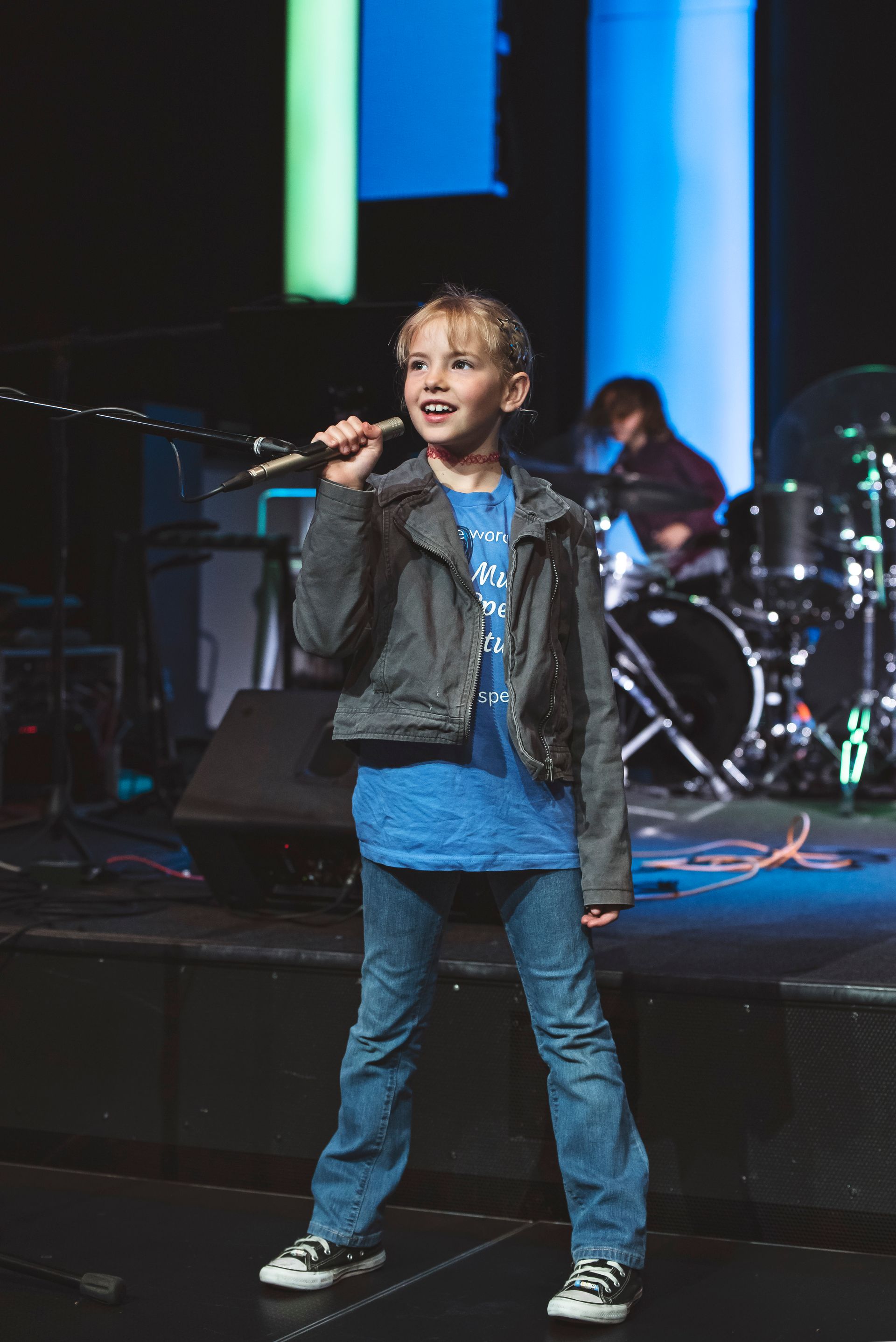 A young boy is singing into a microphone on a stage.