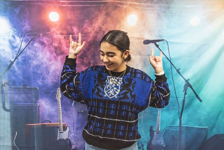 A young woman is dancing on a stage in front of a microphone.