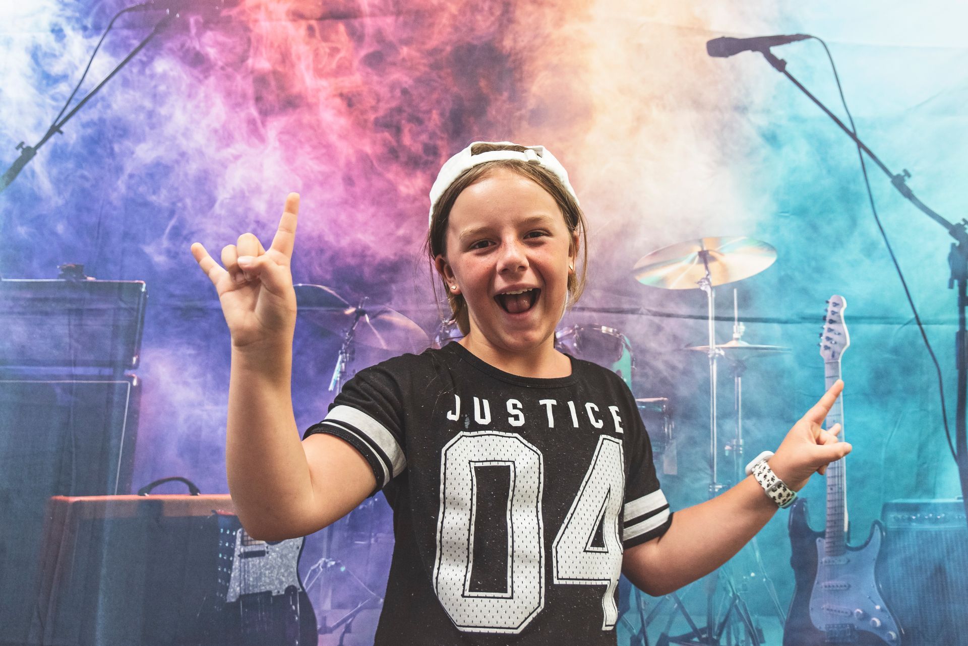 A young girl is making a rock and roll sign in front of a microphone.