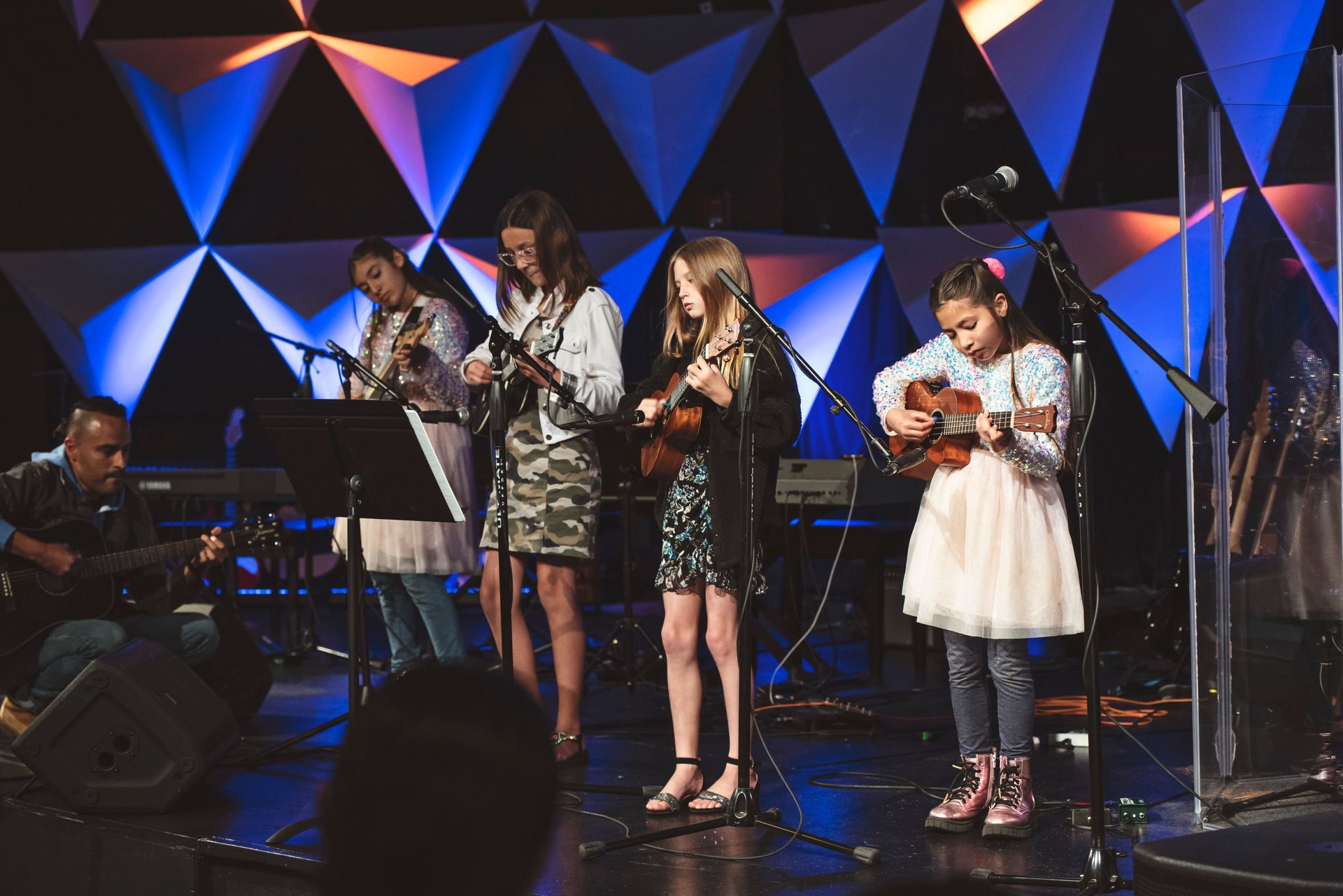 A group of young girls are playing musical instruments on a stage.