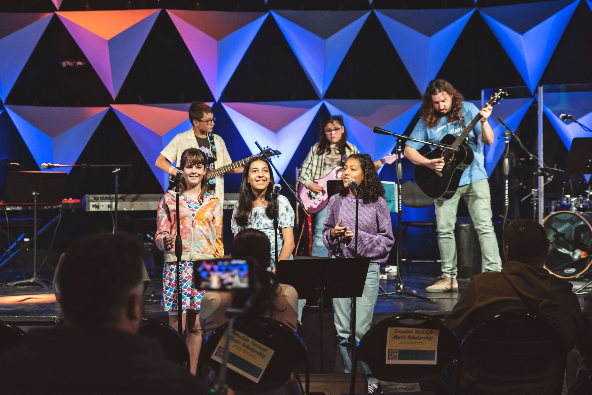 A group of people are standing on a stage playing instruments.