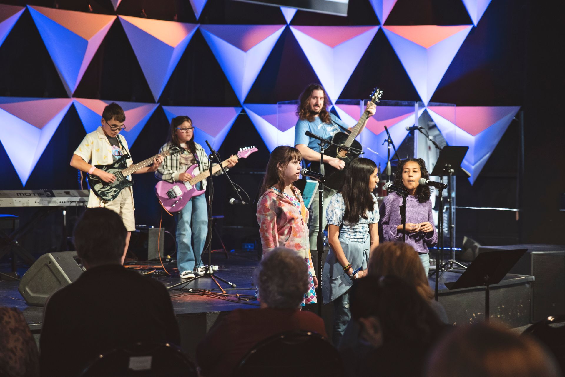 A group of people are playing instruments on a stage in front of a crowd.