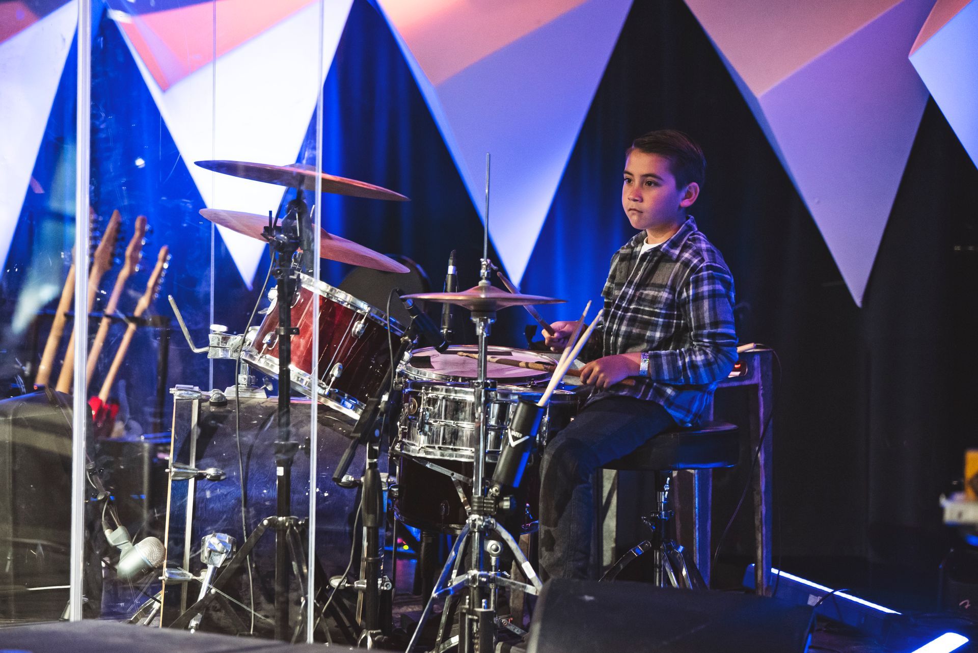 A young boy is playing drums on a stage.
