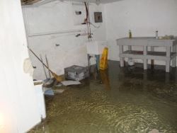 Flooded room with standing water, a table, and cleaning tools against the wall.