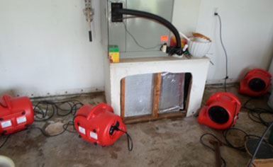Utility room with a white furnace and several red portable blowers on a concrete floor