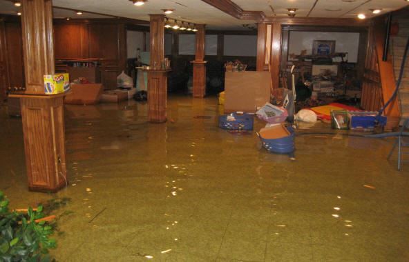 Flooded indoor room with brown water covering the floor and furniture floating around.