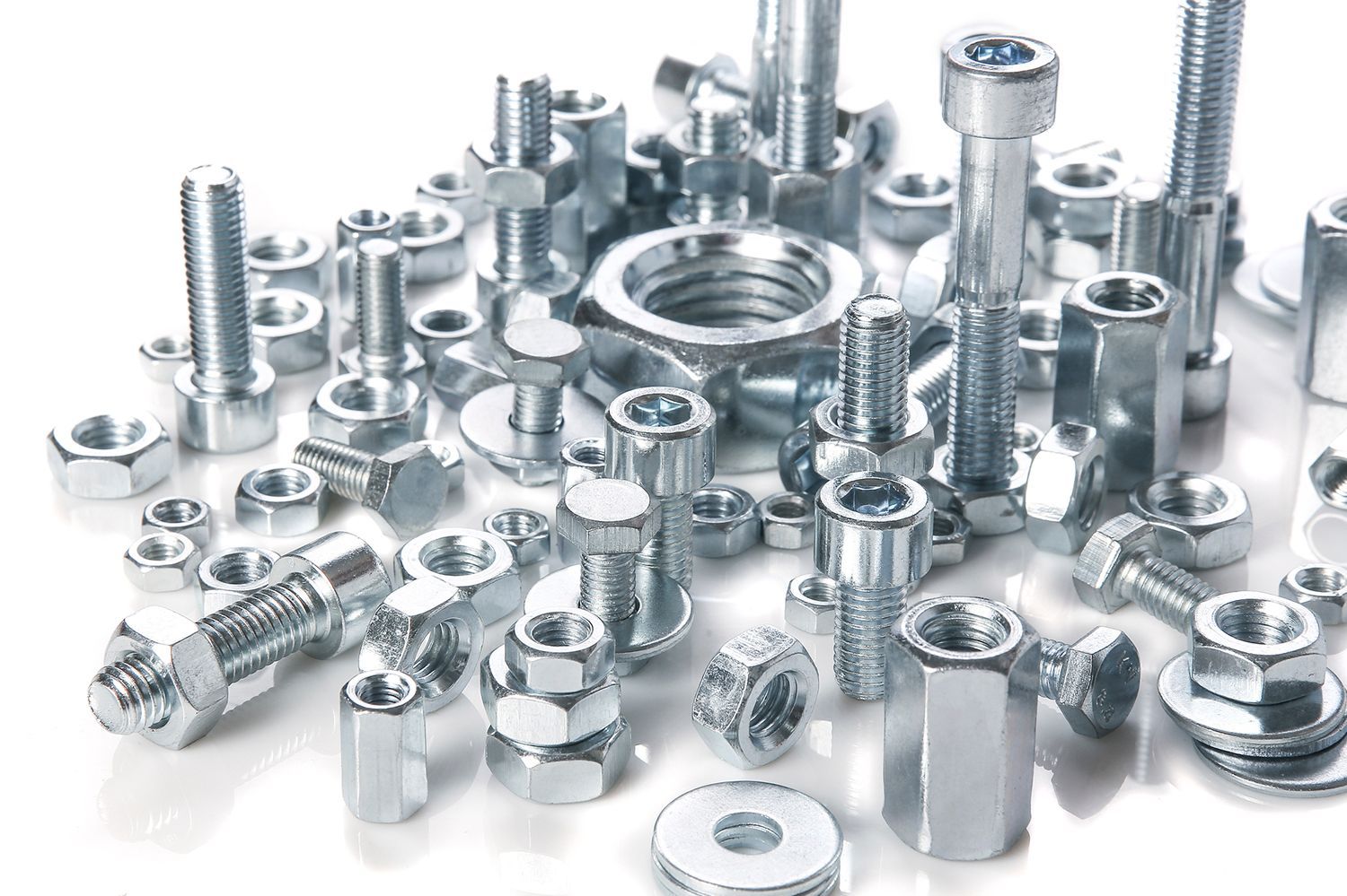 A pile of nuts and bolts on a white surface.
