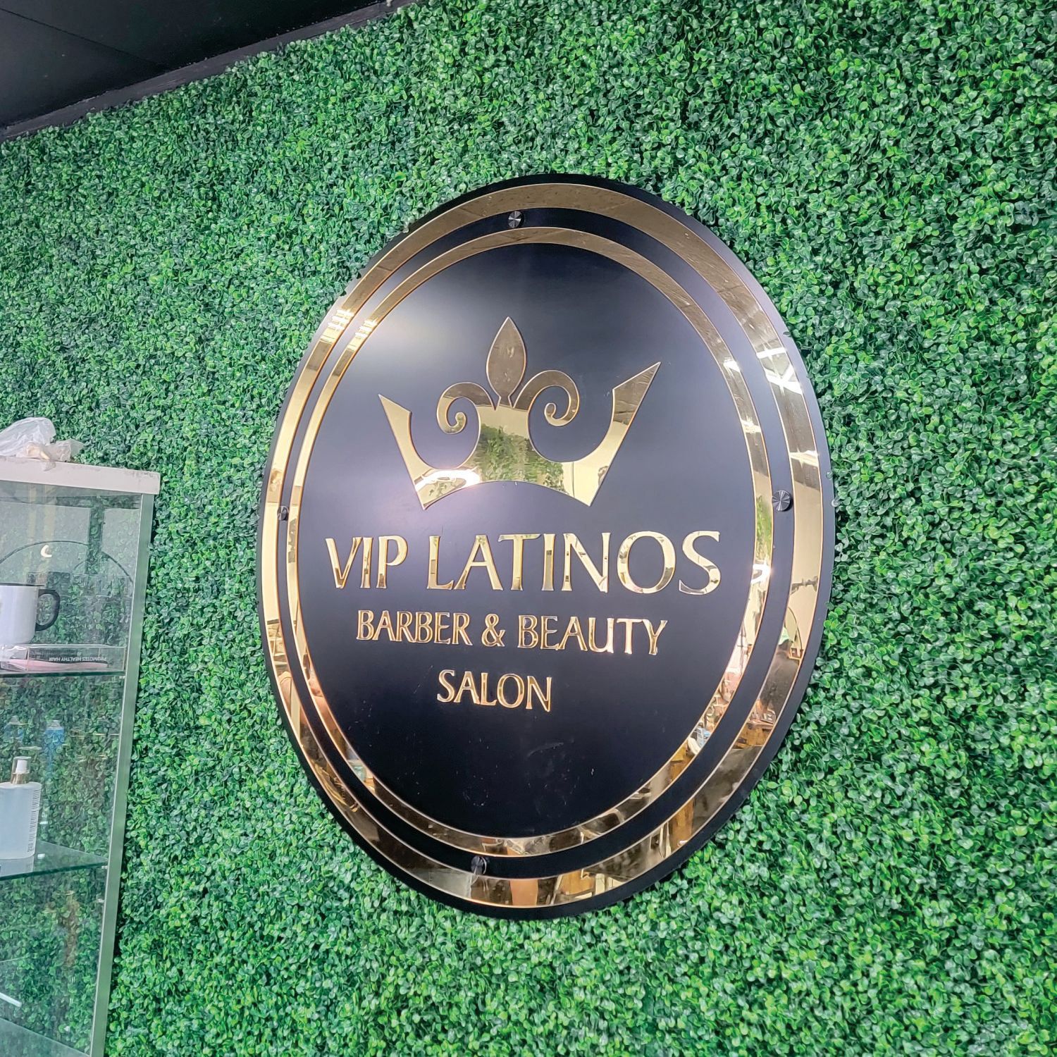 Circular black and gold sign on a green wall. It reads 