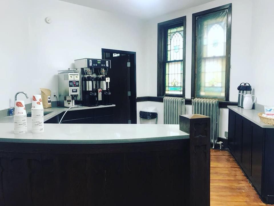 Short North Church. Modern coffee bar with white counter, espresso machine, and two tall windows in a bright room