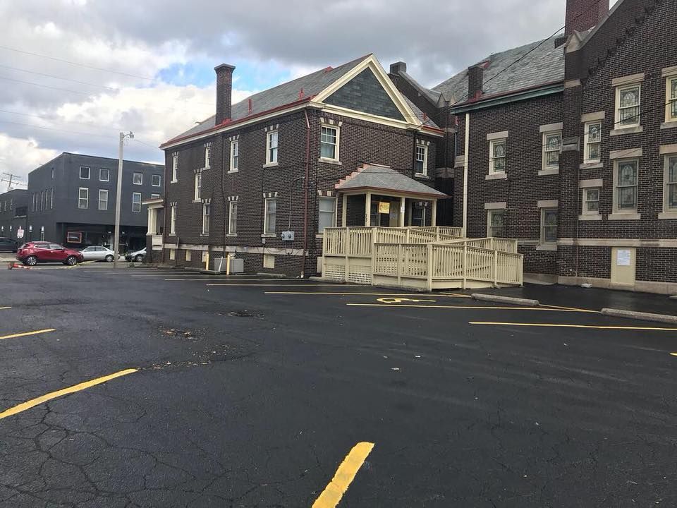 Short North Church. Stone building with beige railings beside a wet asphalt street under cloudy skies.