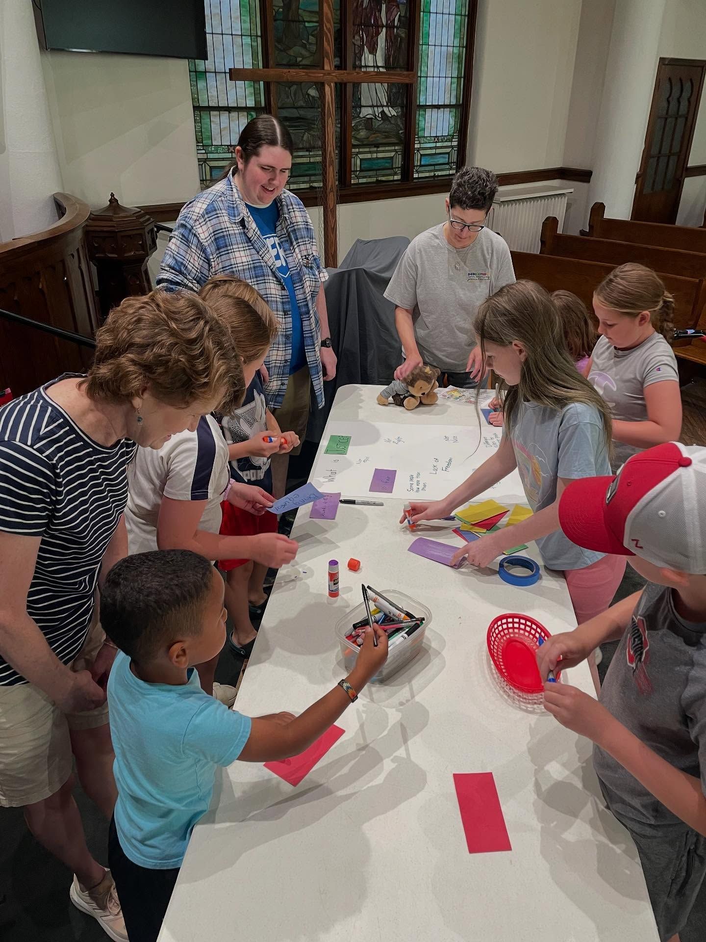 Short North Church. People gathered around a table, working on a craft project with paper and markers.