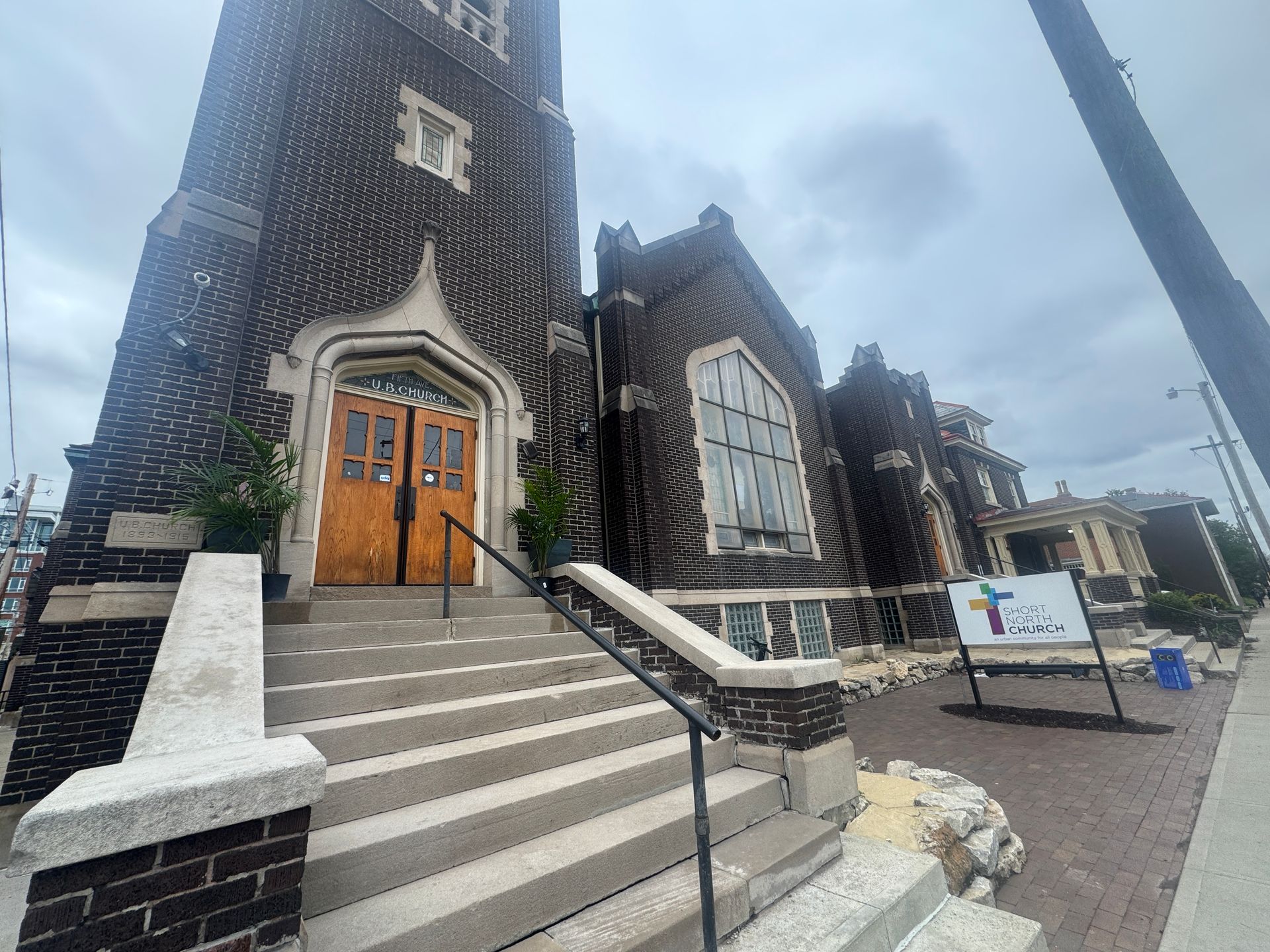 Short North Church. Brick church exterior with steps, arched wooden doors, and cloudy sky