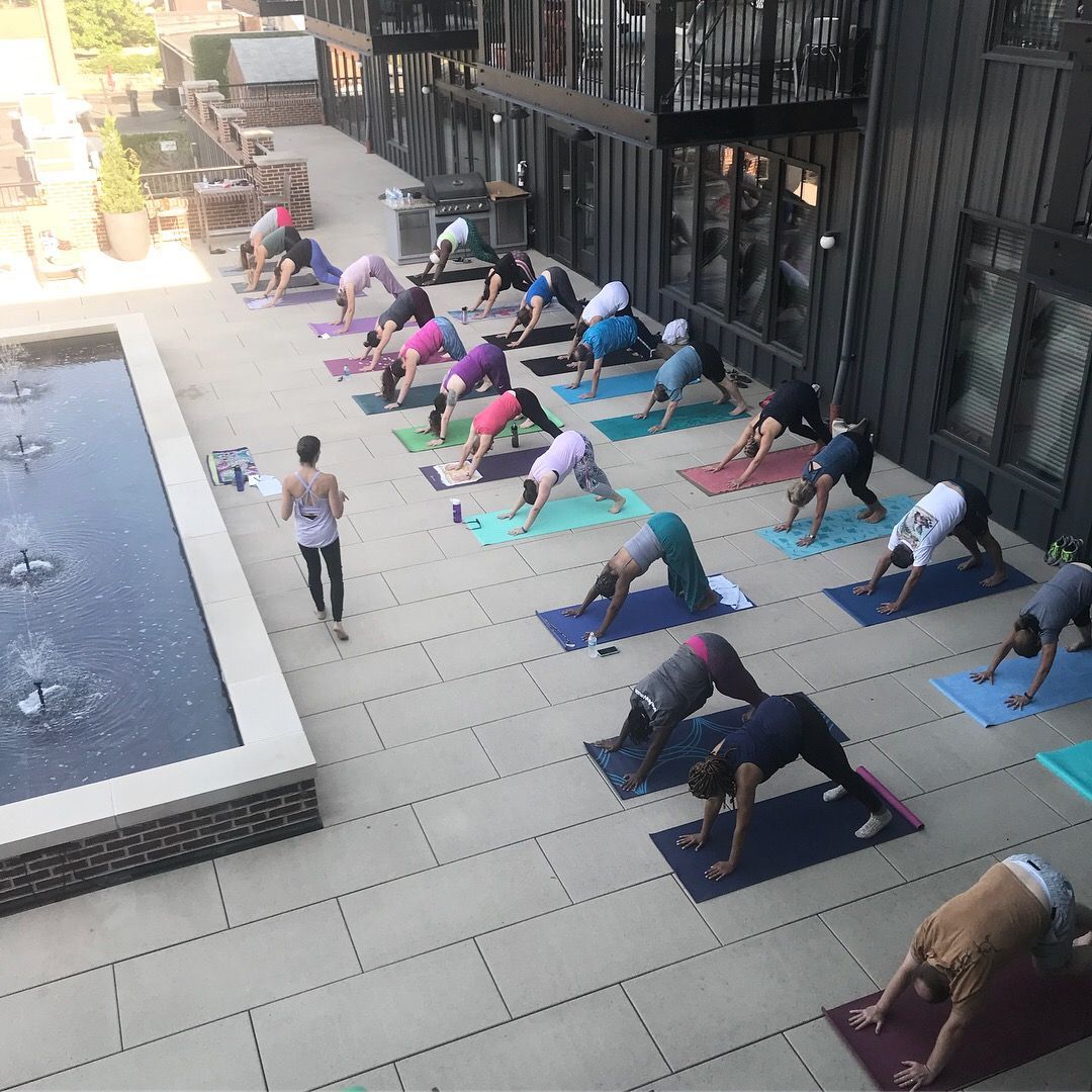 YoWo (yoga+worship) at Short North Church. People doing yoga on mats beside a courtyard pool and building.