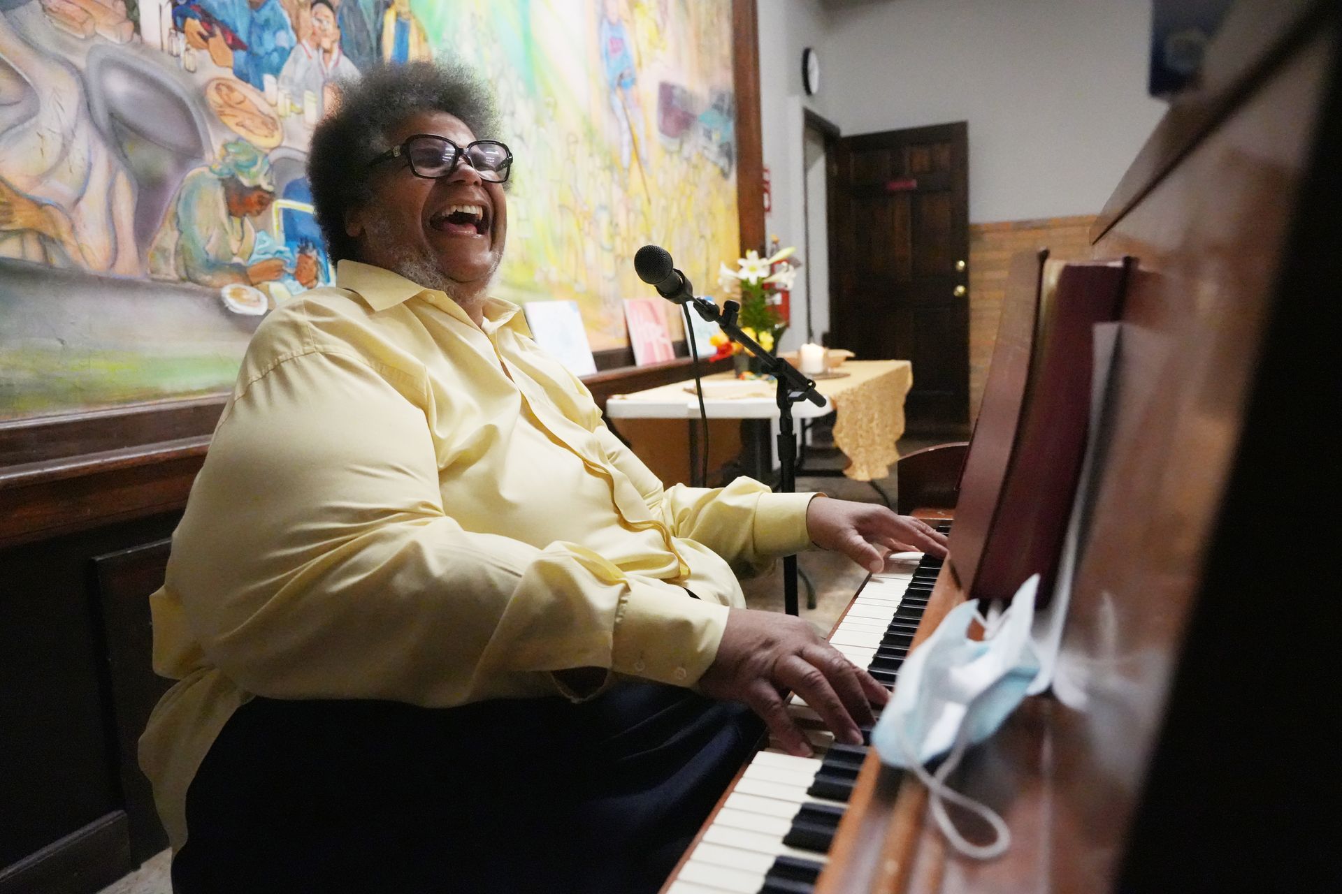 Short North Church. Smiling person in a yellow shirt playing piano in a colorful room