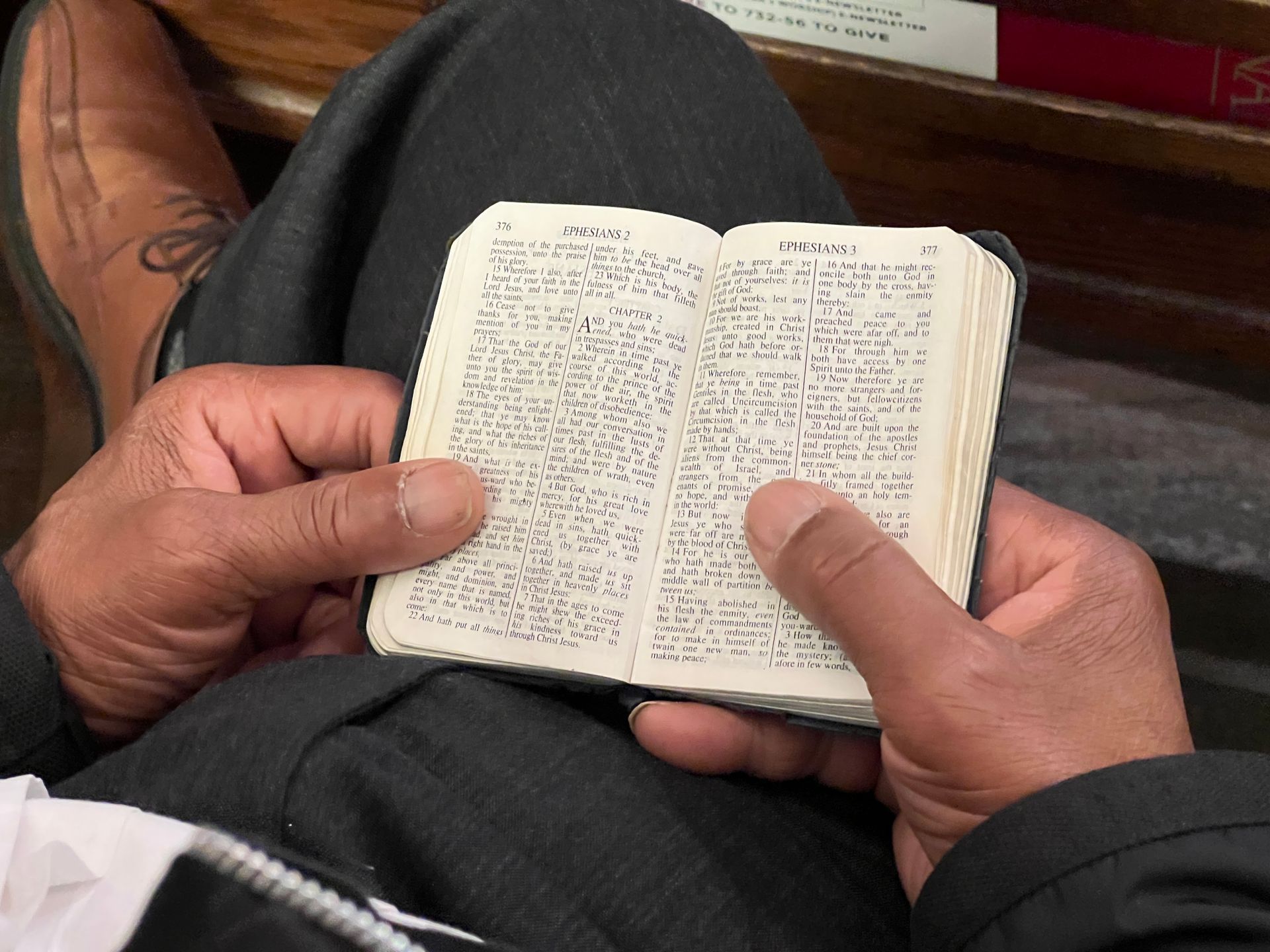 Short North Church. Hands holding a tiny open book with dense text, seated indoors on a lap.