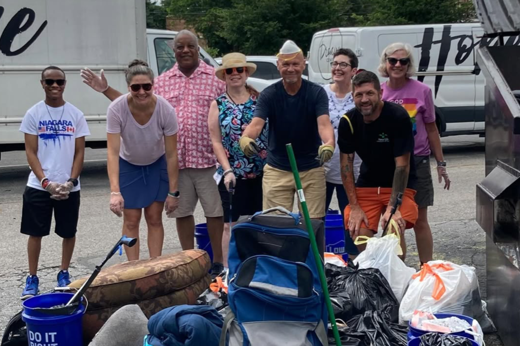 Short North Church. Volunteers posing with collected trash and cleanup gear on a roadside, smiling beside a truck.