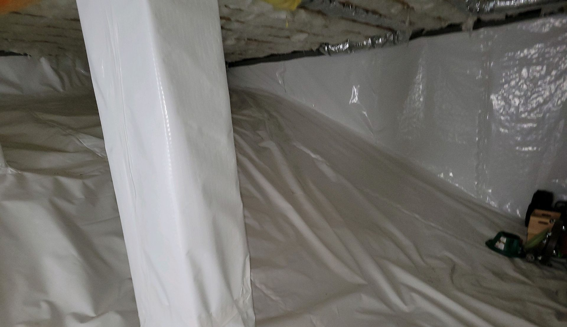 White crawlspace with vapor barrier and insulation.