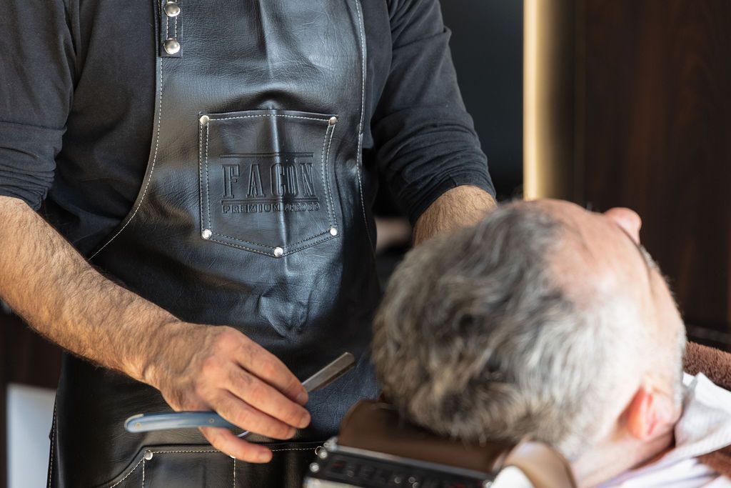 A man is getting his hair cut by a barber in a barber shop.