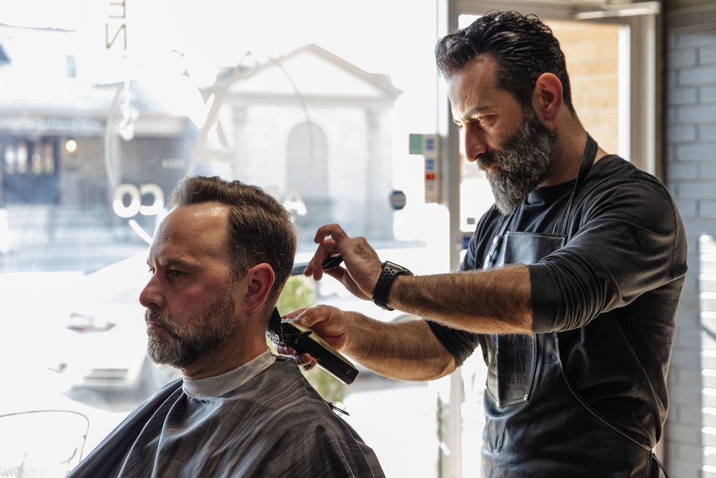 A man is getting his hair cut by a barber in a barber shop.