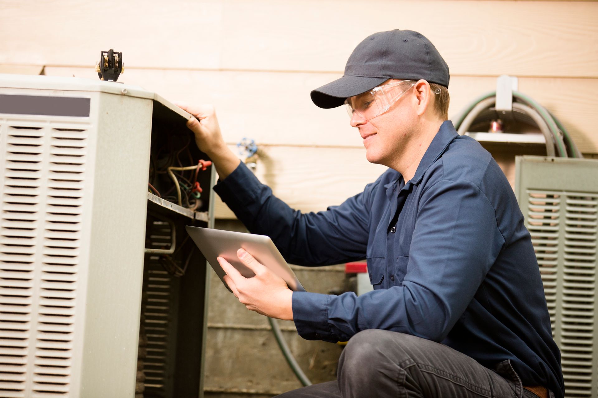 HVAC technician inspecting outdoor conditioning unit with tablet during residential maintenance.