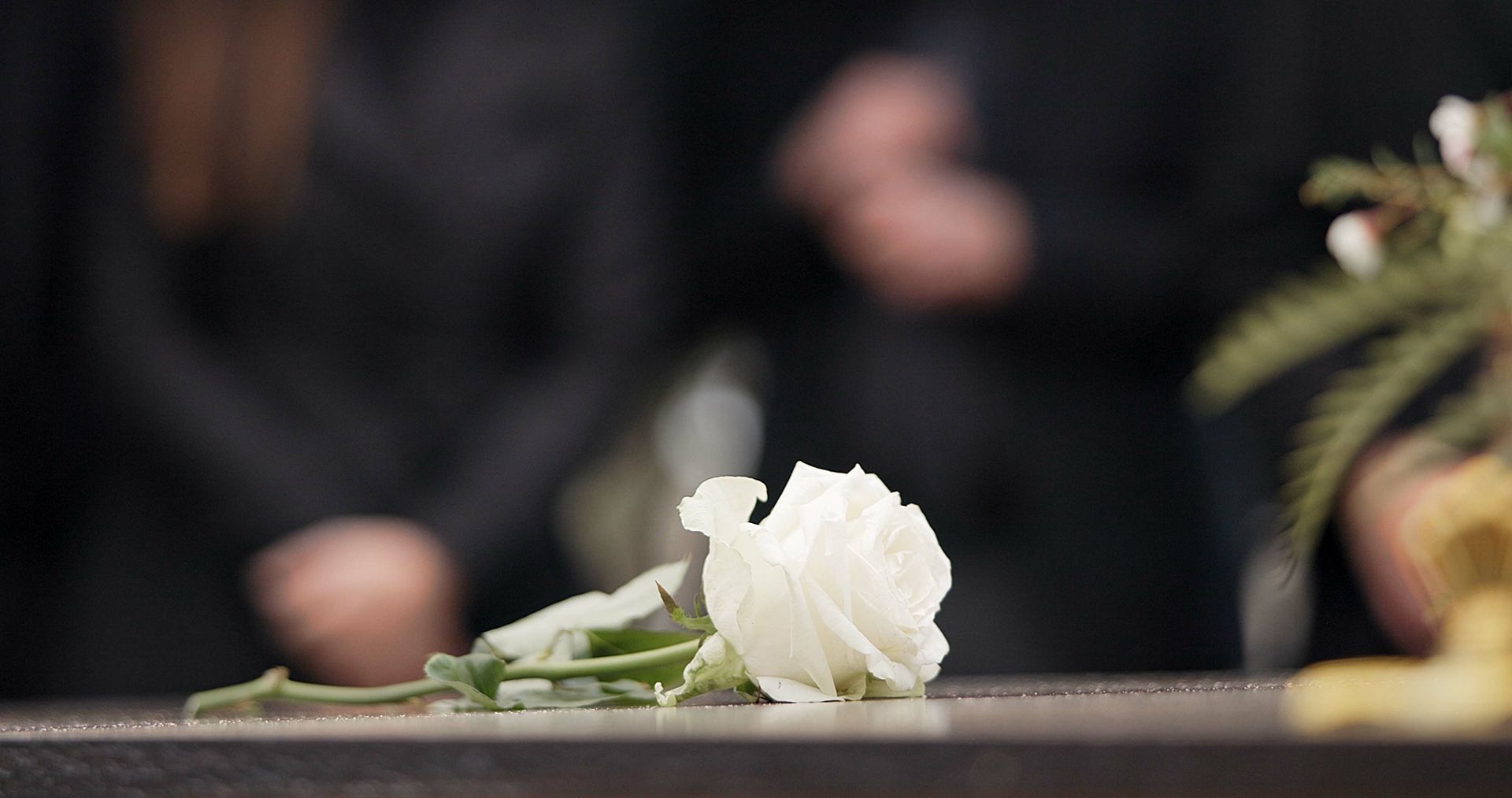 A man in a suit is carrying a coffin in a cemetery.