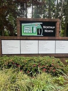 Sign for Northup North office park with directory and map. Green foliage in foreground.