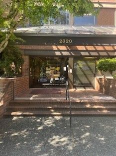 Brick building entrance with stairs, glass door, and address 2320 above.