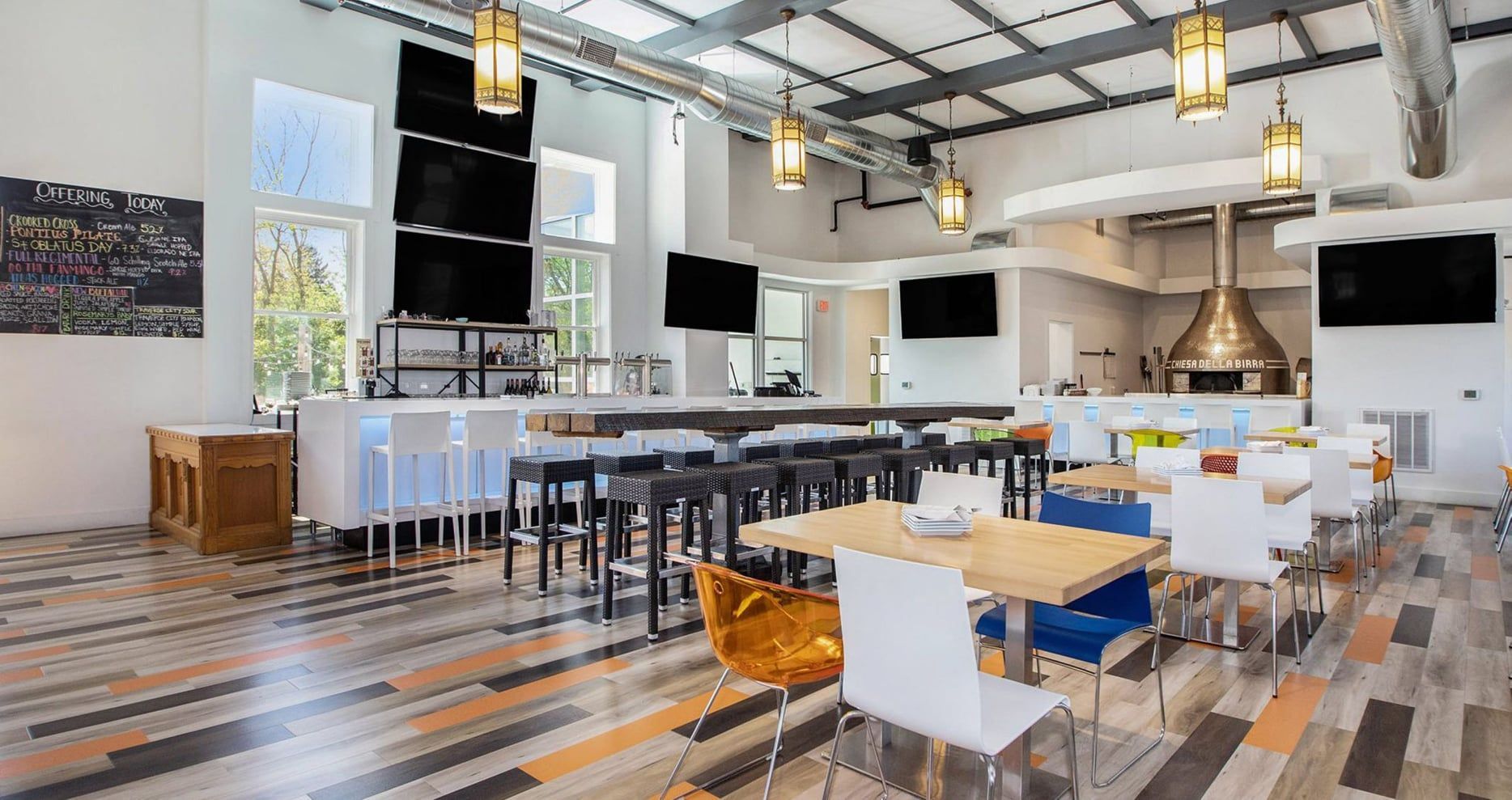 A large dining room with tables and chairs and a bar.