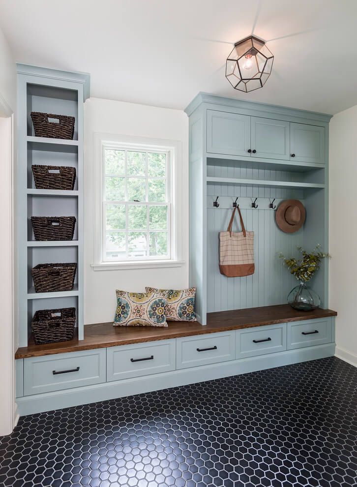 A hallway with a bench , shelves , drawers and a window.