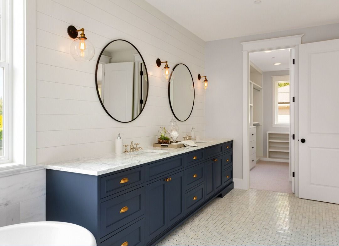 A bathroom with two sinks , two mirrors and a bathtub.