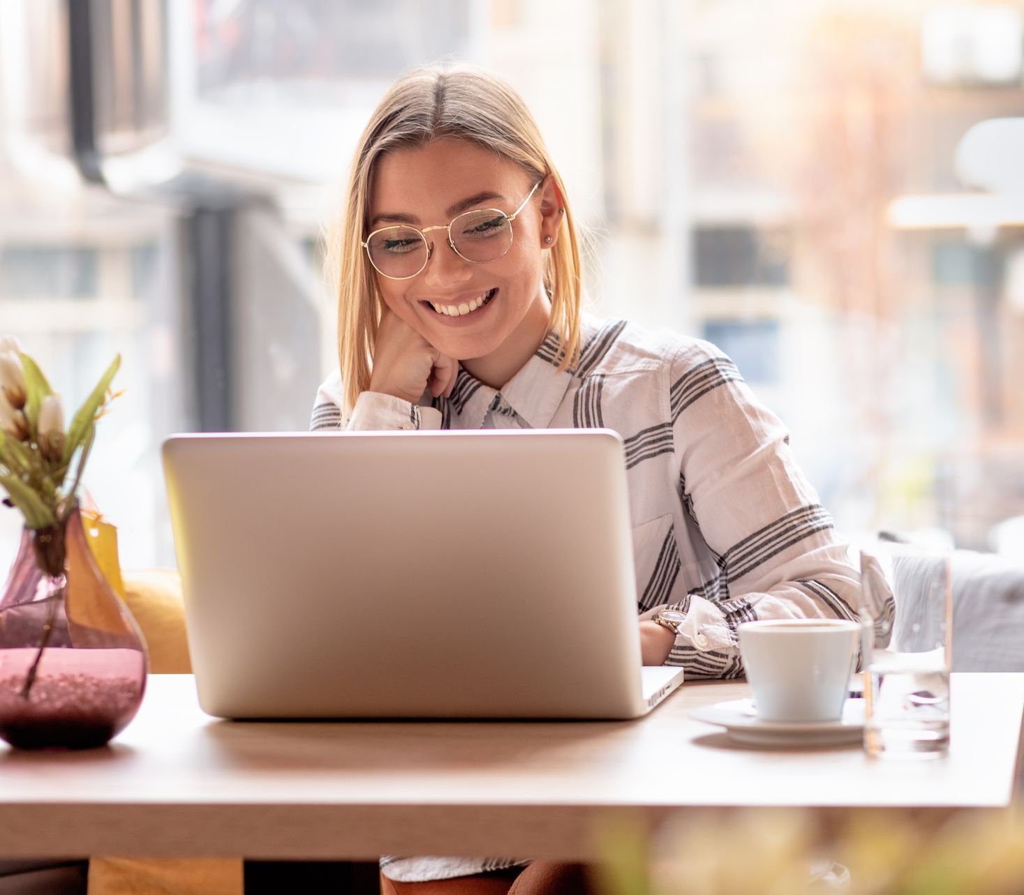 A woman is sitting at a table using a laptop computer.
